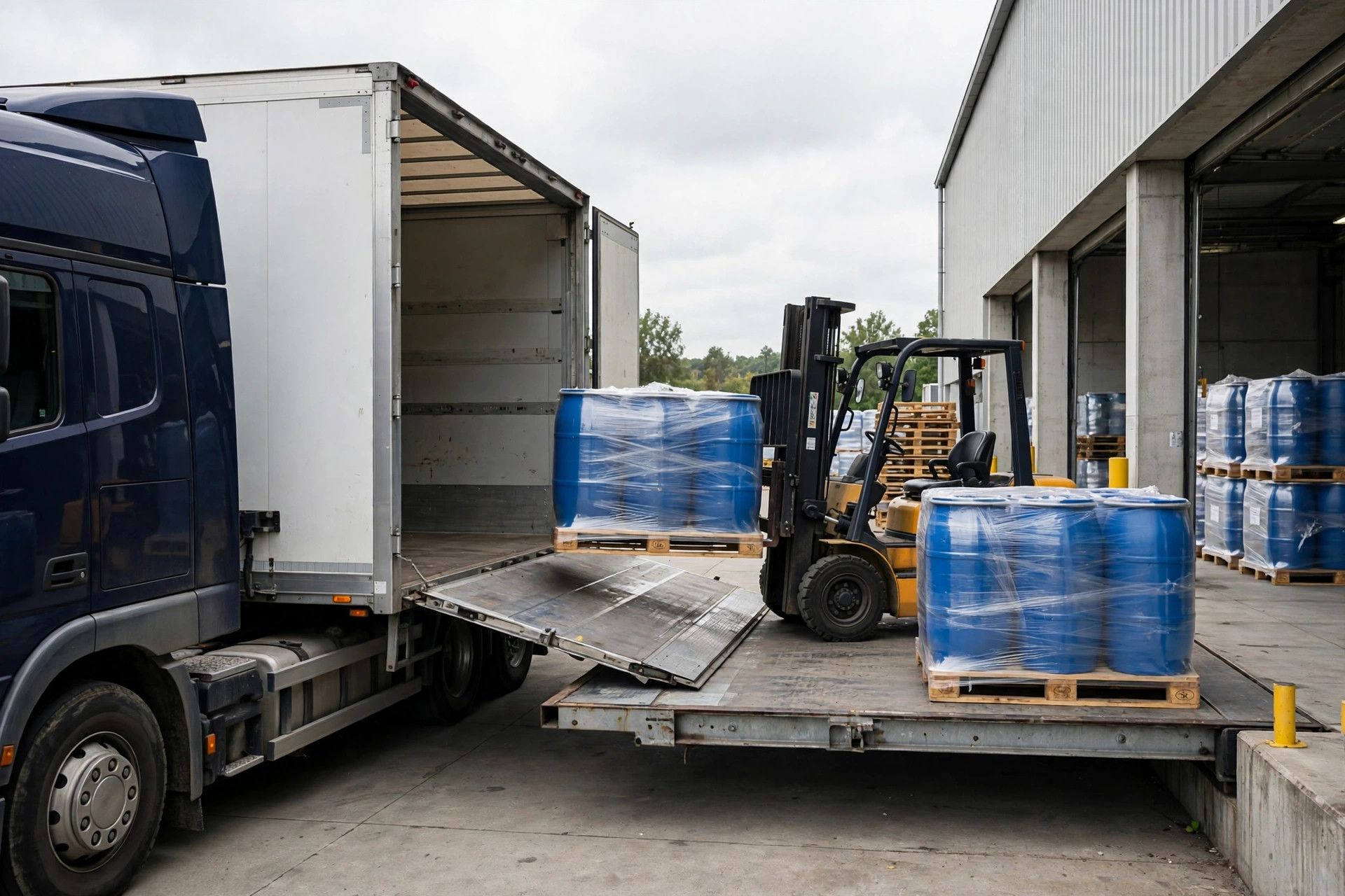 Semi truck being loaded with palletized agricultural chemical drums at a warehouse dock